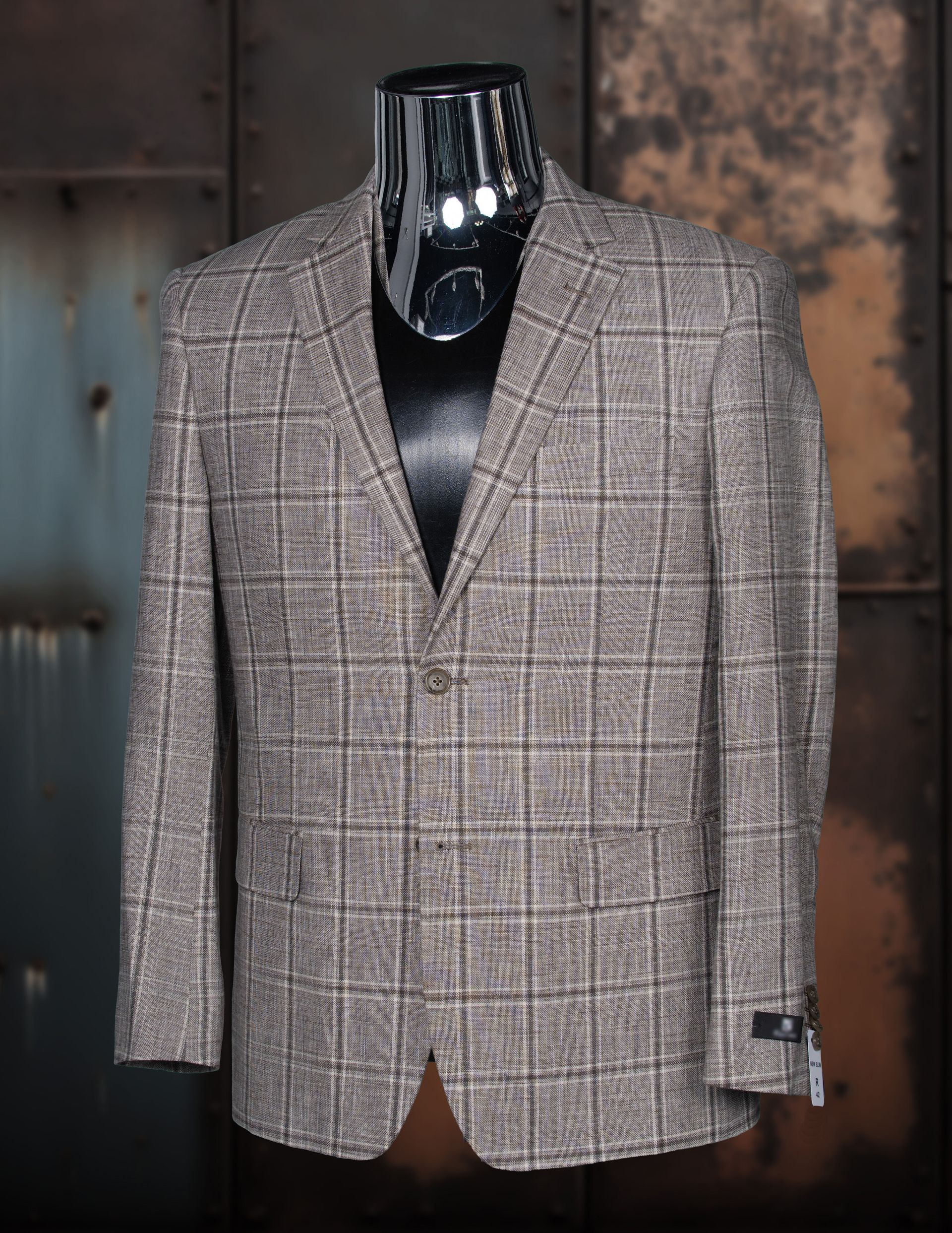 Plaid sport coat on a mannequin. Brown, gray and black colors. Buttoned up, with a dark colored collar.