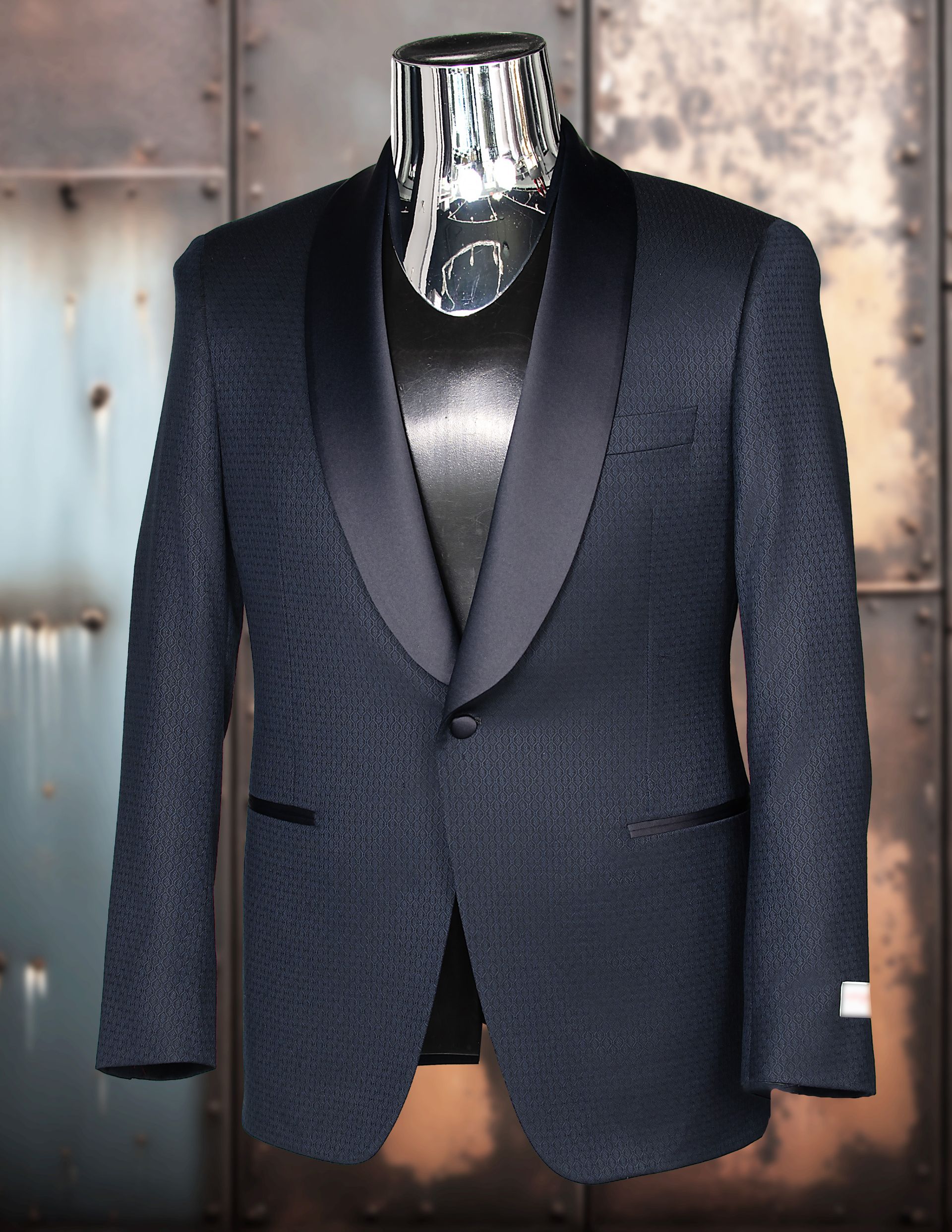 Blue patterned tuxedo jacket on a mannequin, with black satin lapel, against a metallic background.