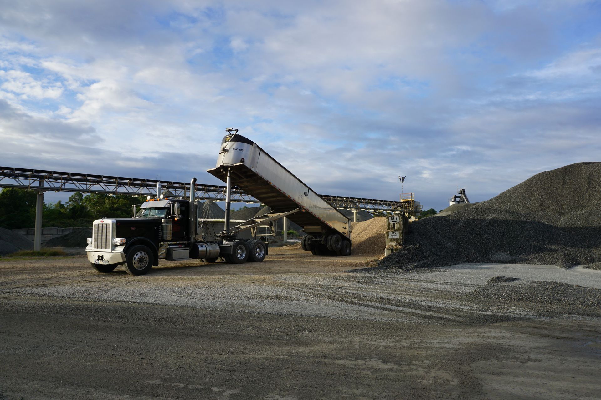 A dump truck is being loaded with gravel in a gravel yard.