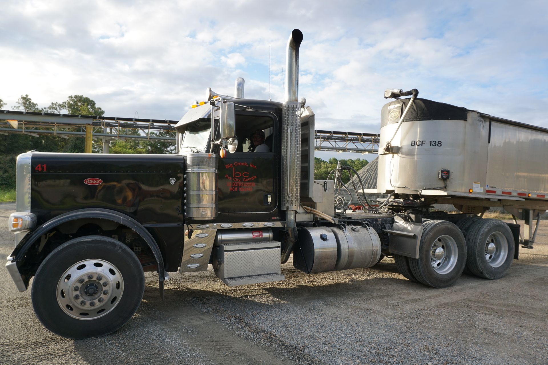 A black semi truck is parked next to a white trailer.