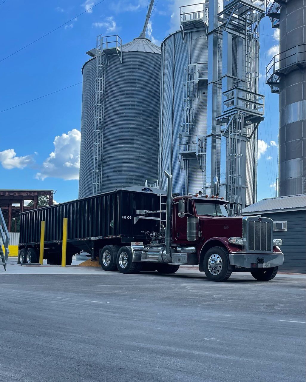 A red semi truck is parked in front of silos