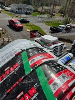 A bunch of bags of roofing material are sitting on top of a roof.