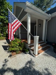 An american flag is flying on the porch of a house.