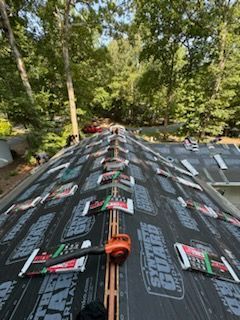 A roof with a lot of shingles on it and trees in the background.