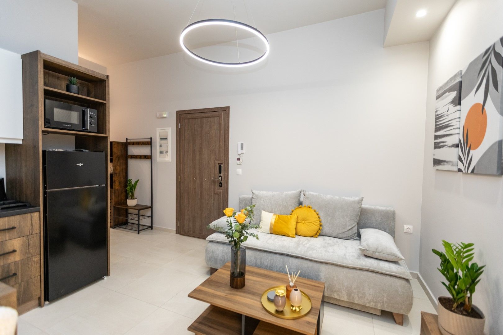 Small living area with a sofa, wooden coffee table, and a black refrigerator.