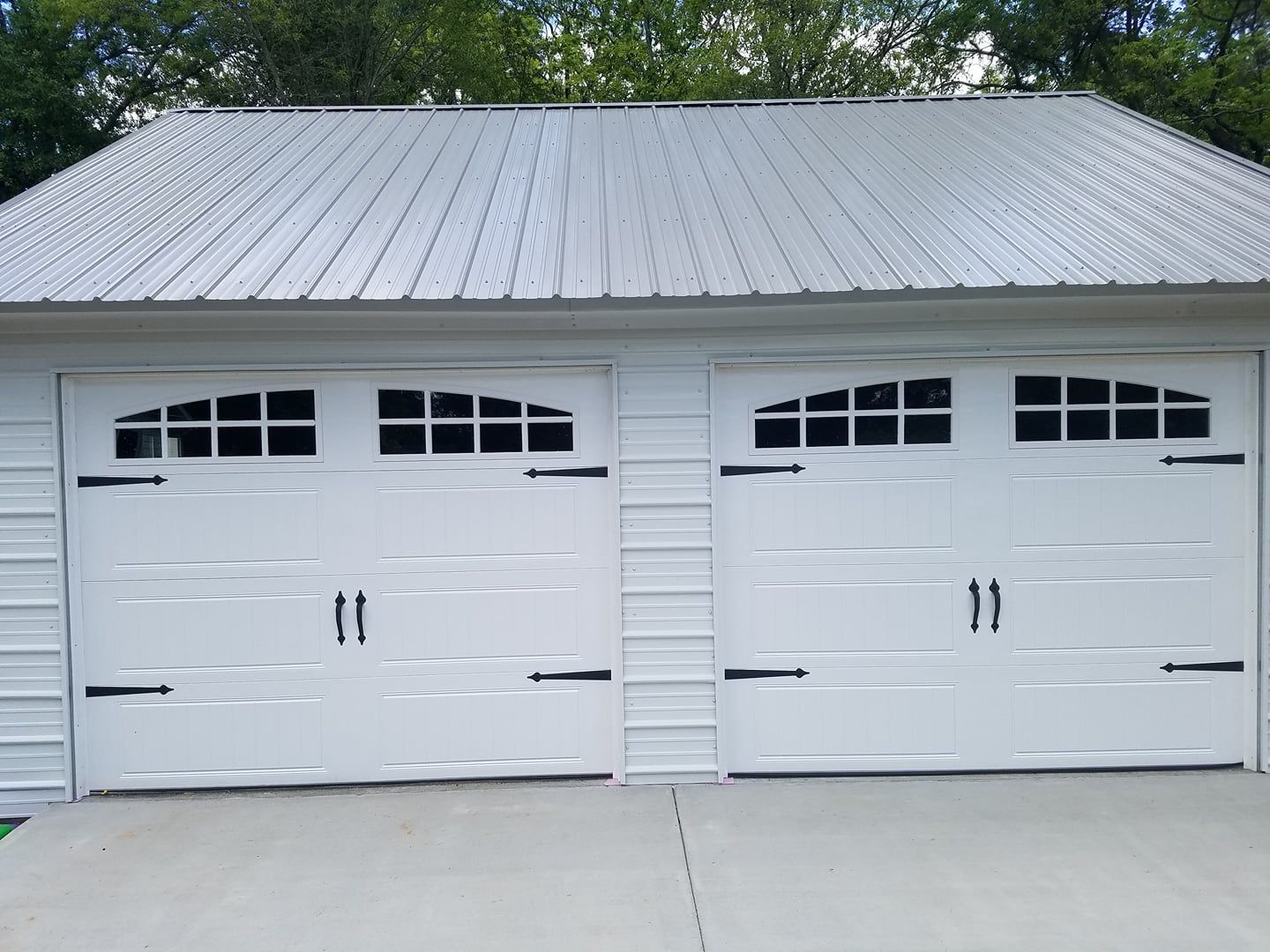 White double garage doors with decorative black hardware and windows.