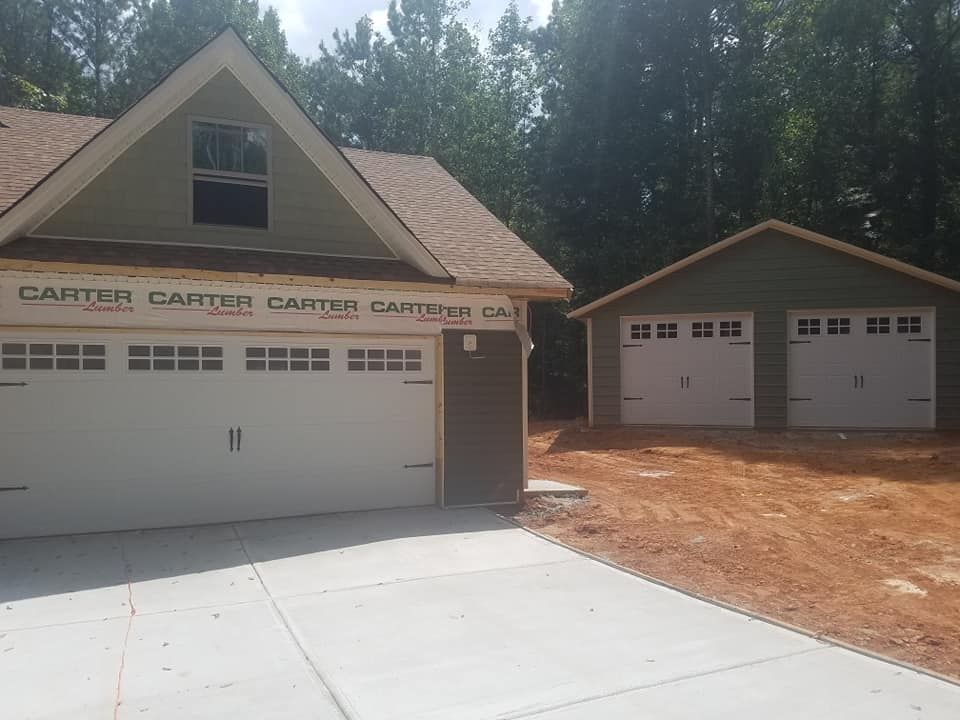 Two-car garage attached to a house and a detached one-car garage, all with white garage doors.