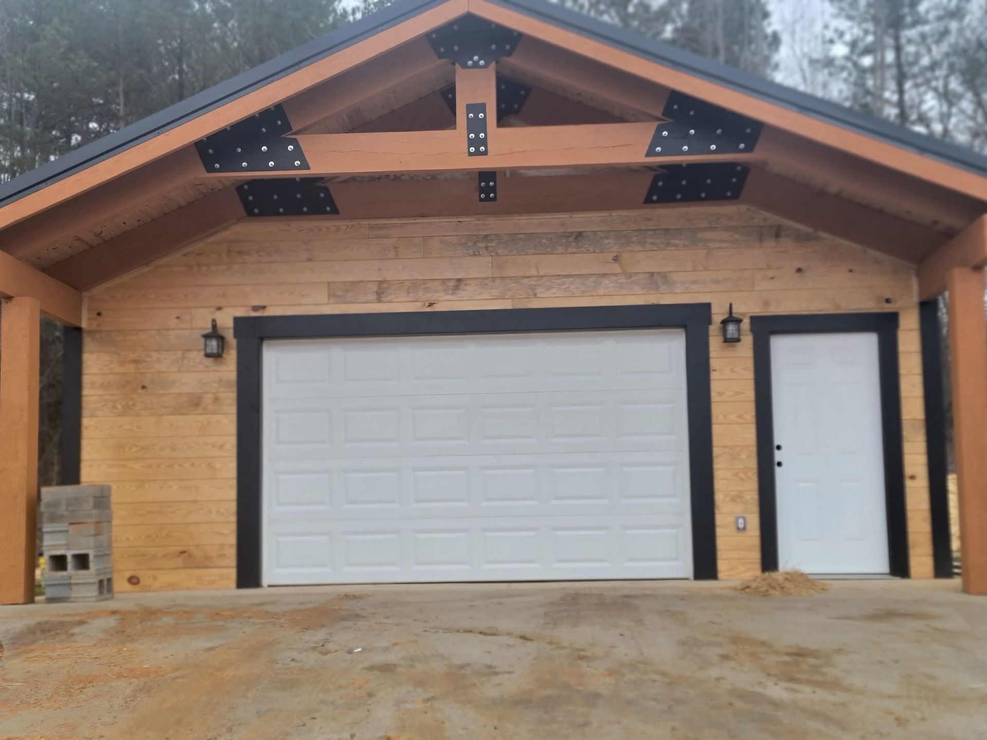 Garage with white door, black trim, and wooden beams.