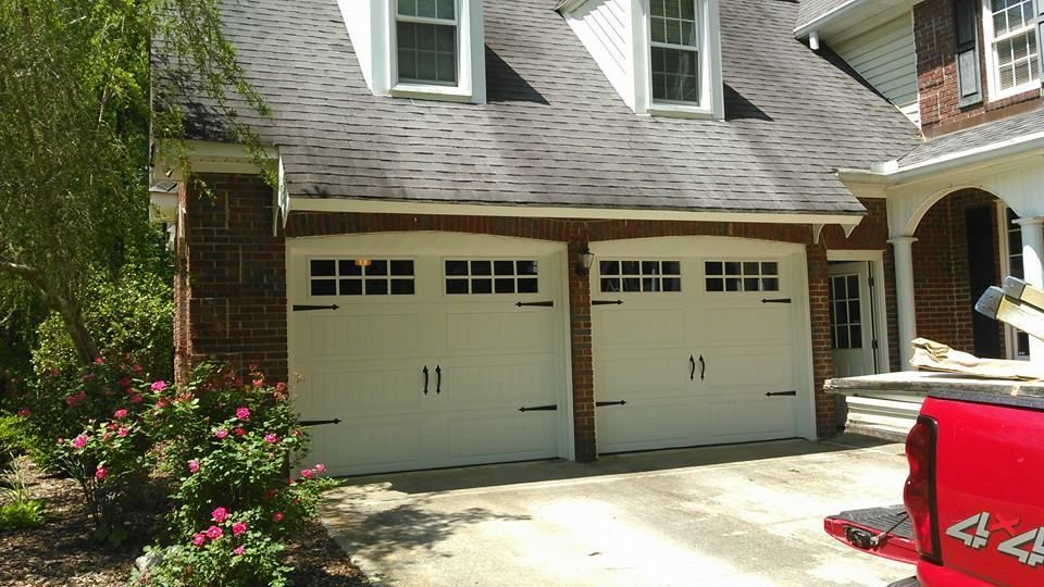 Two-car garage with white doors, black hardware, and brick exterior.  A red truck is partially visible on the right.