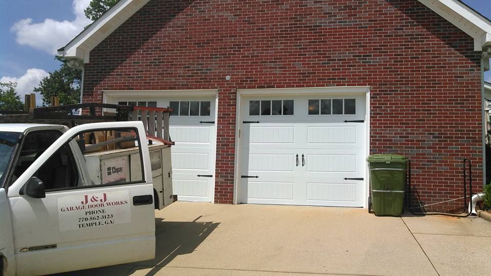 White garage doors on brick building with a white truck parked in the driveway.