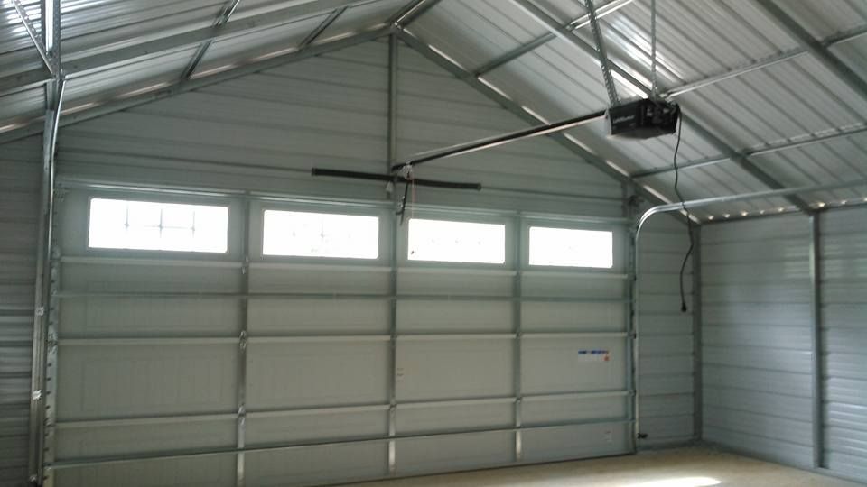 Interior view of a metal garage with a closed garage door and windows above.