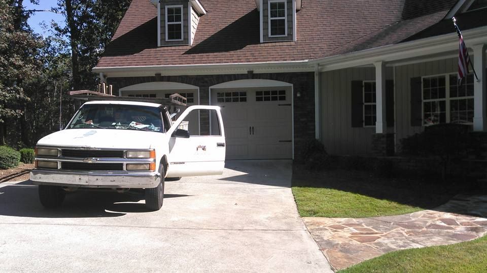 White truck parked in front of a house, door open. Garage and windows visible.