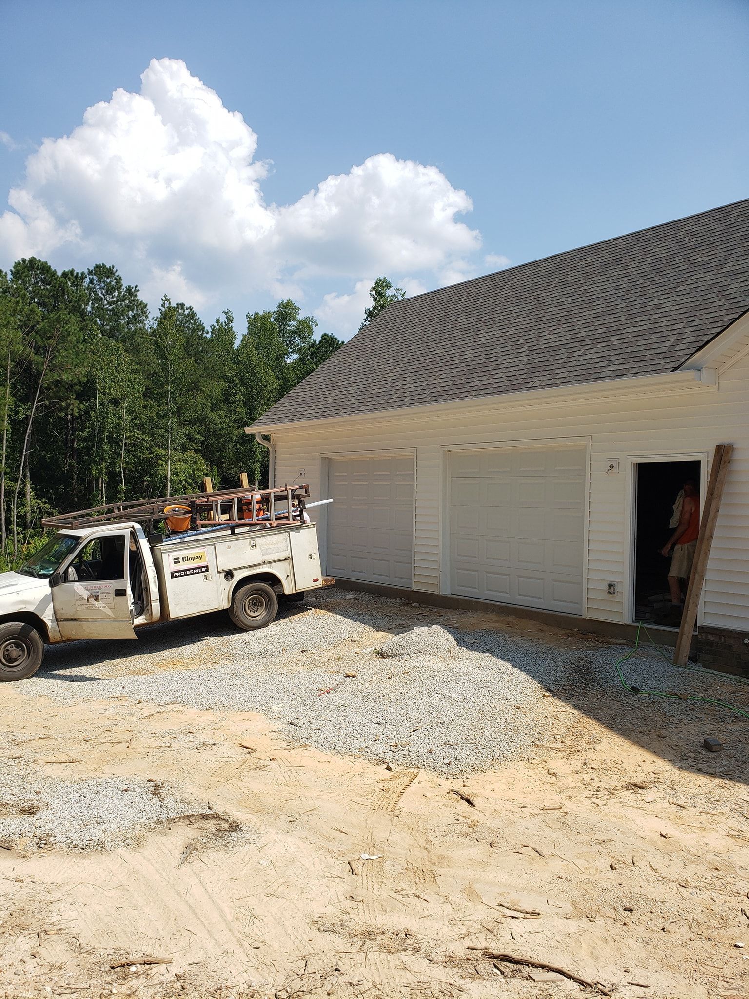 White work truck next to a building under construction; gravel pile in front.
