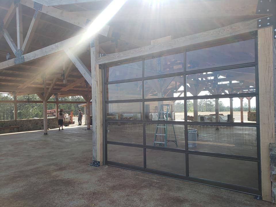 Glass door on a wooden frame, leading to an outdoor pavilion. Bright sunlight.