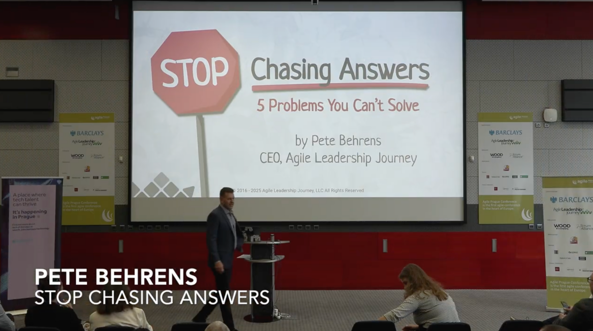 Pete Behrens presents “Stop Chasing Answers: 5 Problems You Can’t Solve” on a screen at an indoor conference.