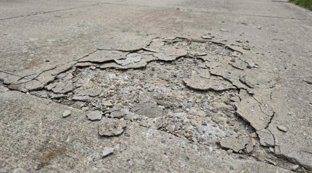 Cracked, peeling asphalt on a damaged road surface.