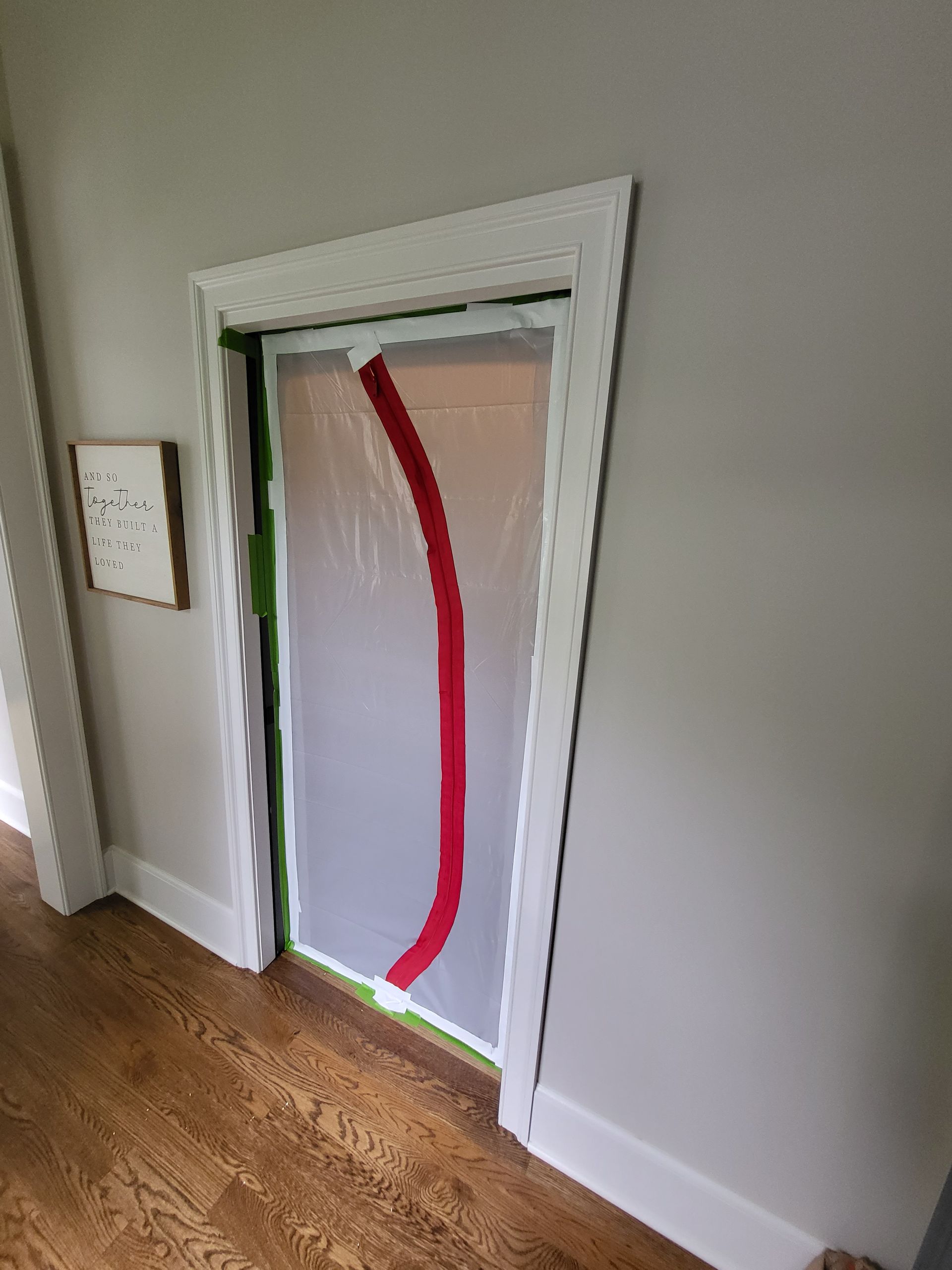 A door is covered in plastic and has a red stripe on it