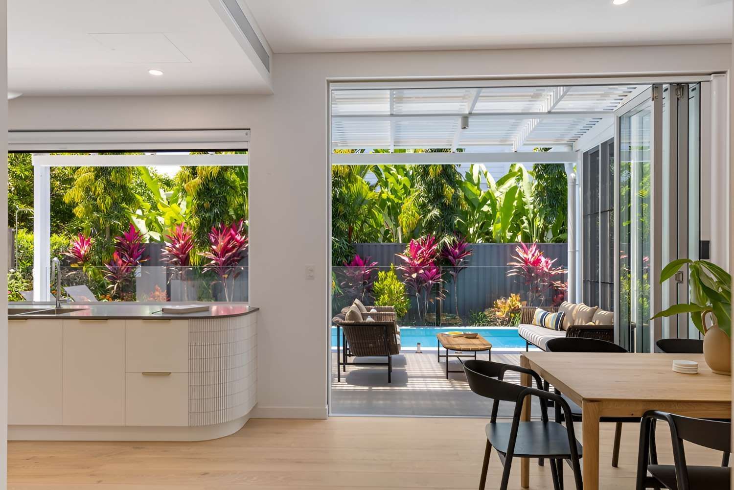 A Kitchen With a Table and Chairs and a View of a Swimming Pool — Kitchens by CCJS in Bungalow, QLD