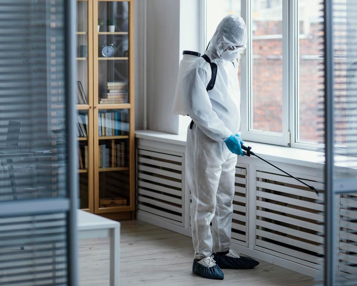 A man is cutting a hedge with a hedge trimmer in front of a house.