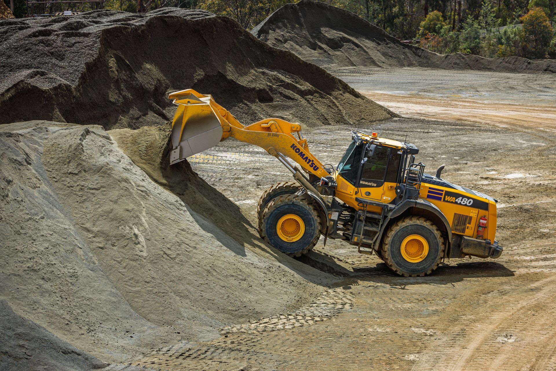 Yellow front loader filling a dump truck with gravel at a construction site