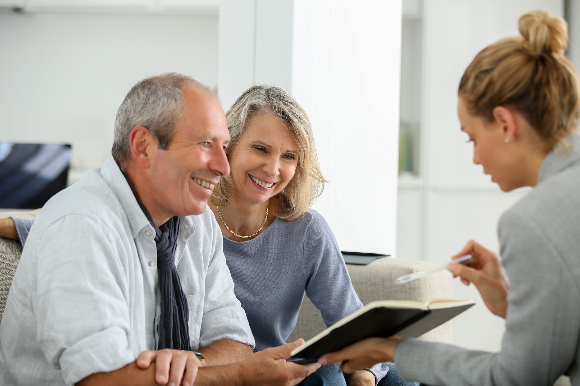 Couple reviewing documents with a professional in a home setting.