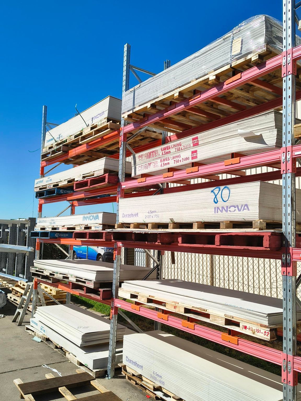 Shelves stacked with construction materials on pallets, against a bright blue sky — Kev's Group QLD in Kawana, QLD