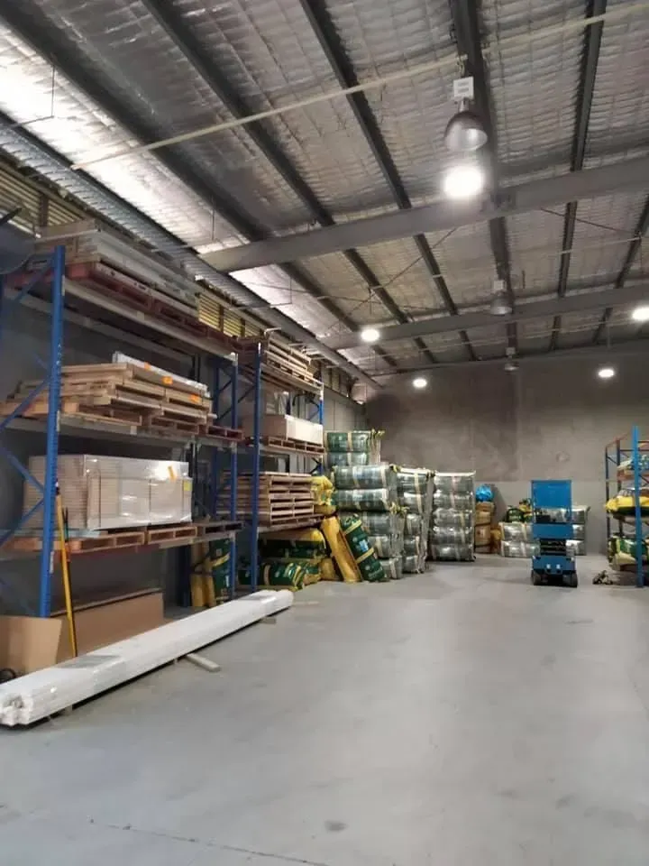 Warehouse Interior With Shelves of Materials, Metal Roof, and Lighting — Kev's Group QLD in Kawana, QLD
