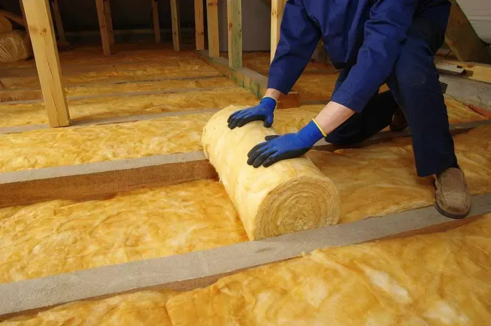Person Installing Yellow Insulation in an Attic — Kev's Group QLD in Kawana, QLD