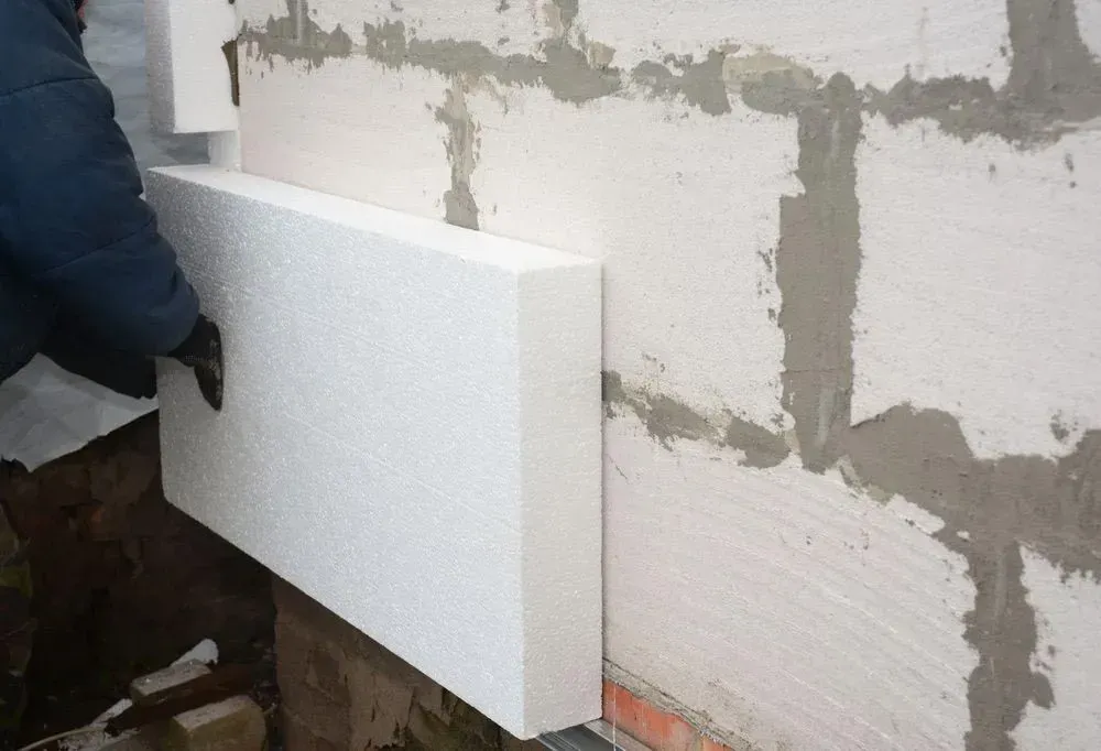 Person Installing White Foam Insulation on a Brick Wall — Kev's Group QLD in Kawana, QLD