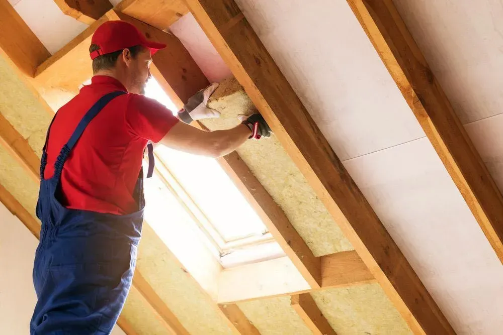 Man in Red Shirt and Blue Overalls Installing Insulation in an Attic — Kev's Group QLD in Kawana, QLD