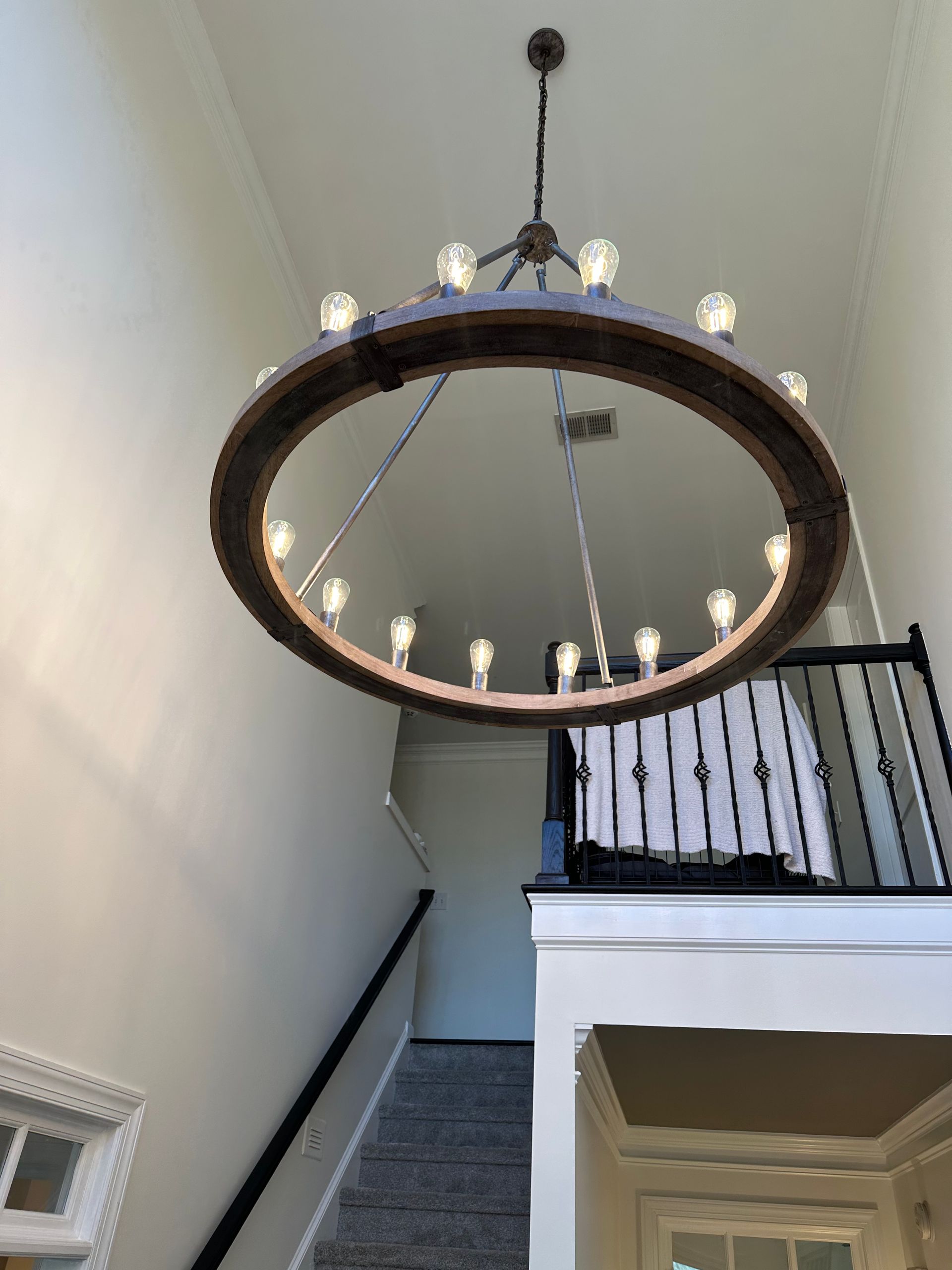 Large circular chandelier lighting fixture professionally installed in home entryway
