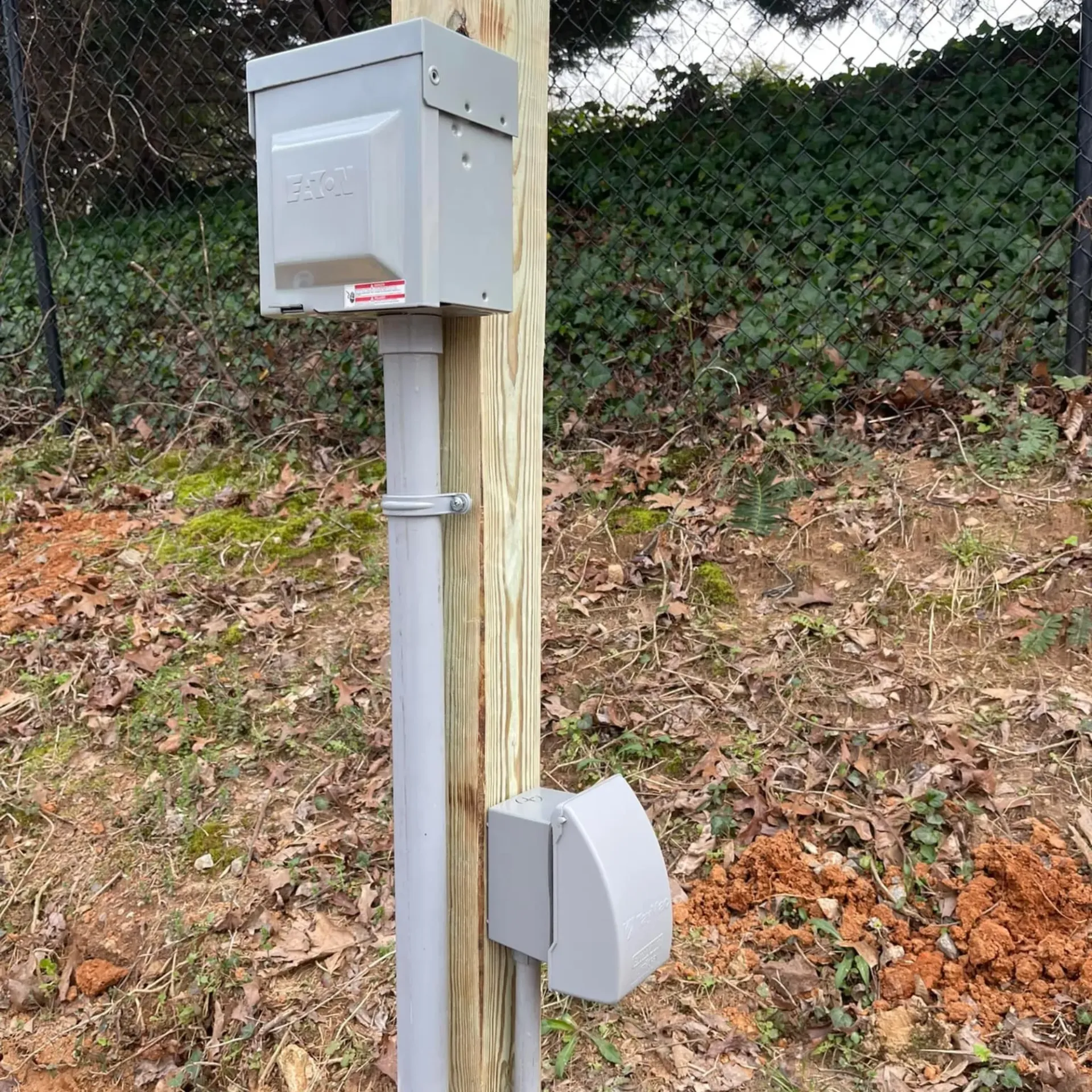 Mounted weatherproof outdoor electrical outlet and service box on wooden post