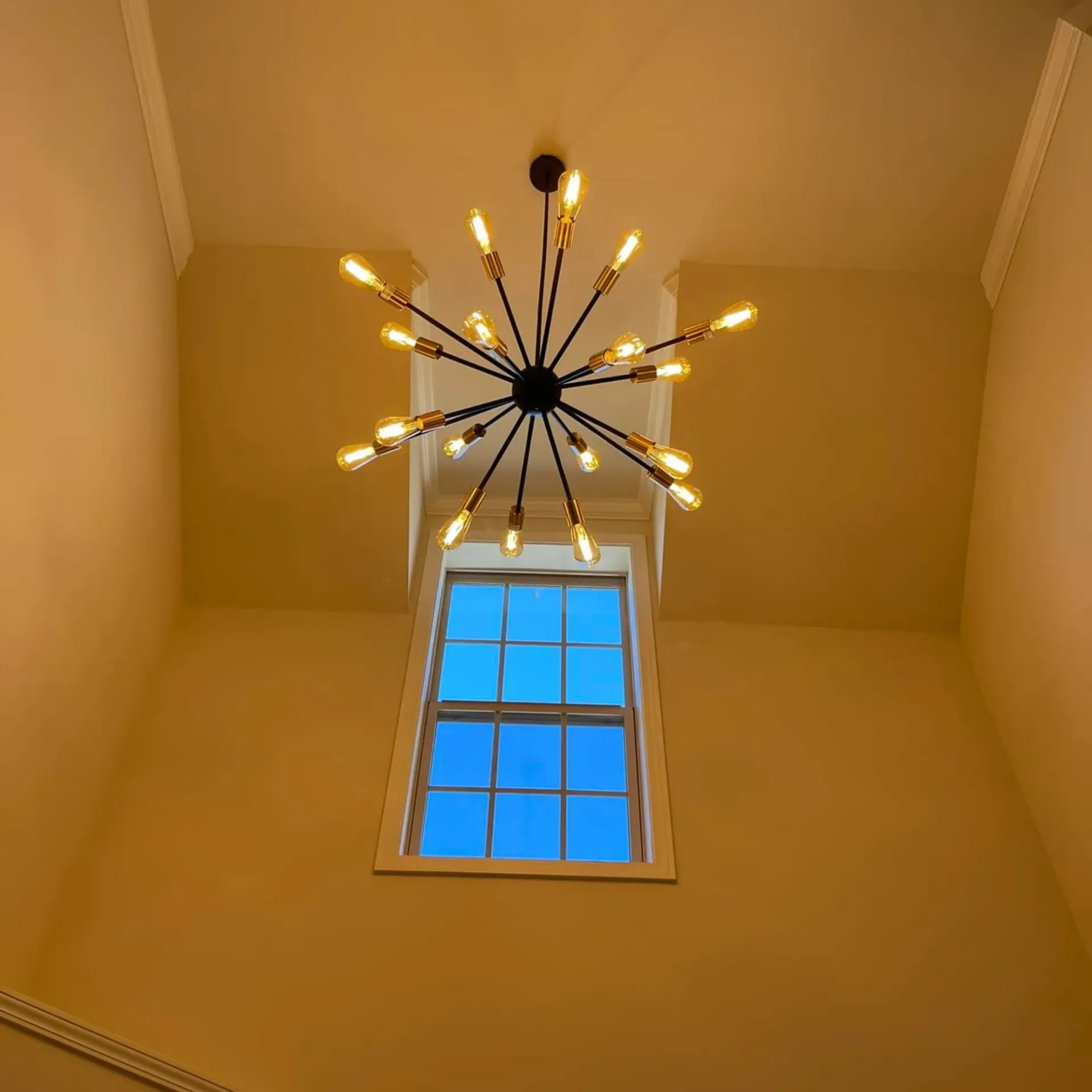 Modern chandelier lighting fixture professionally installed in vaulted ceiling entryway