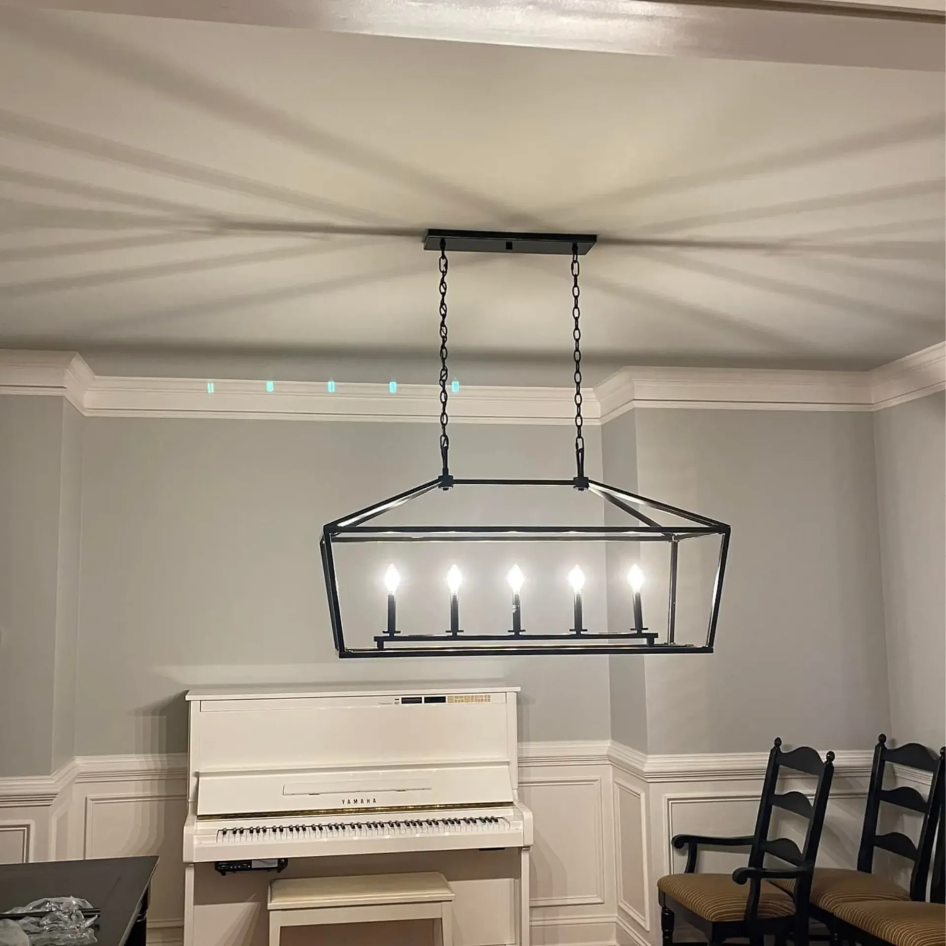 Decorative chandelier lighting professionally installed over piano in dining room