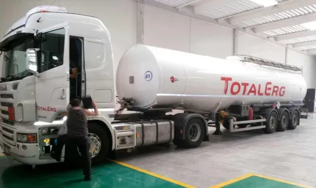 Autocisterna bianca della TotalEnergies parcheggiata in un magazzino, con due persone vicino alla cabina.