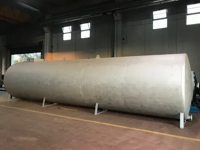 Grande serbatoio di stoccaggio cilindrico argentato in un magazzino.