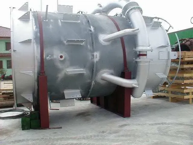 Grande cisterna industriale argentata su supporti rossi, all'aperto.