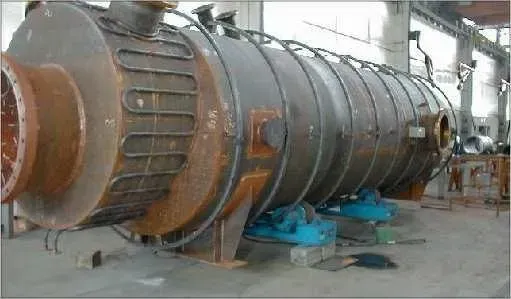 Grande serbatoio cilindrico industriale in una fabbrica, sostenuto da blocchi blu.