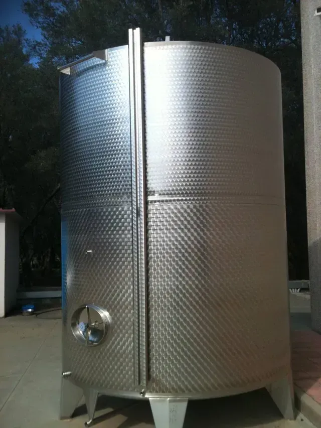 Grande serbatoio per la fermentazione del vino in acciaio inox per esterni con trama a rombi, colore argento metallizzato.