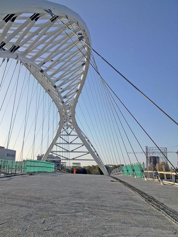 Moderno ponte sospeso bianco contro il cielo azzurro. Il ponte è ricoperto di ghiaia.
