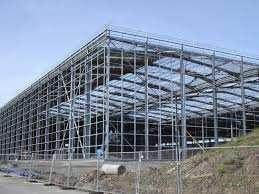 Struttura in acciaio di un grande edificio in costruzione contro un cielo azzurro e terso.