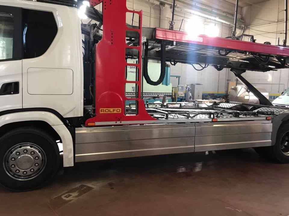 Camion bianco con braccio della gru rosso e scala, in un garage.