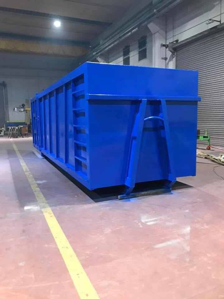 Contenitore blu per rifiuti industriali in un magazzino.