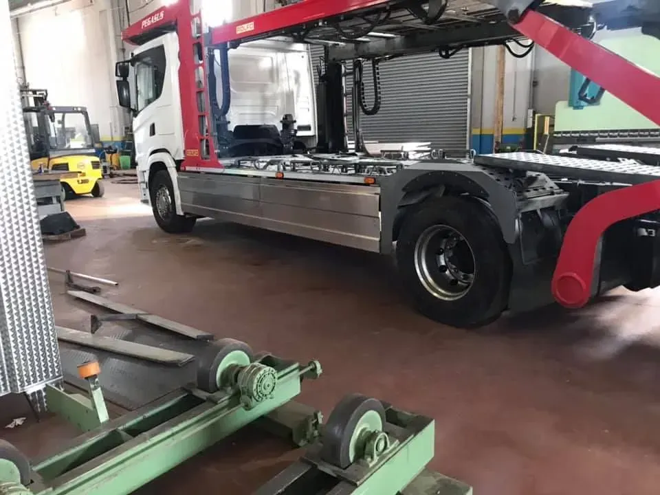 Carro attrezzi all'interno di un garage. Un camion rosso e bianco con pianale e pneumatici neri.