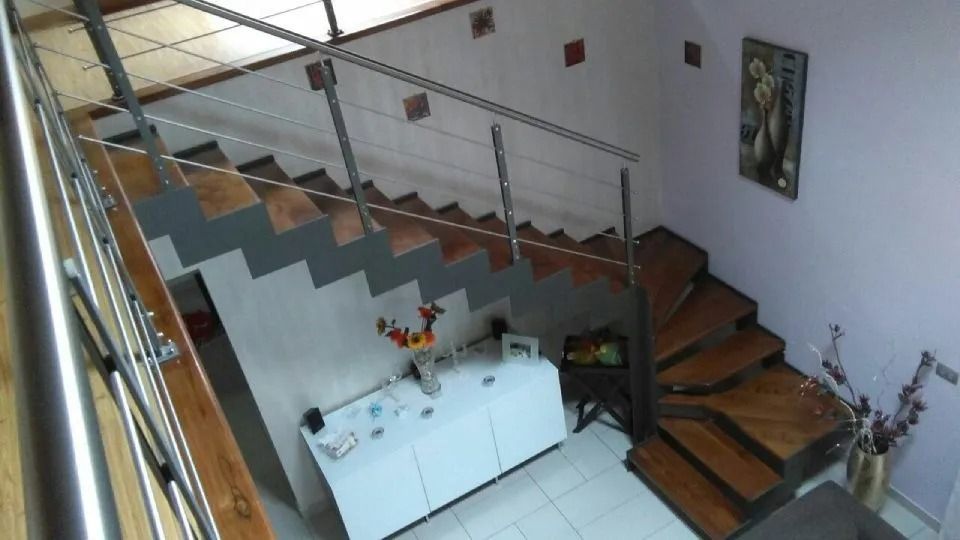 Scala con gradini in legno e ringhiera in metallo che conduce al piano superiore.