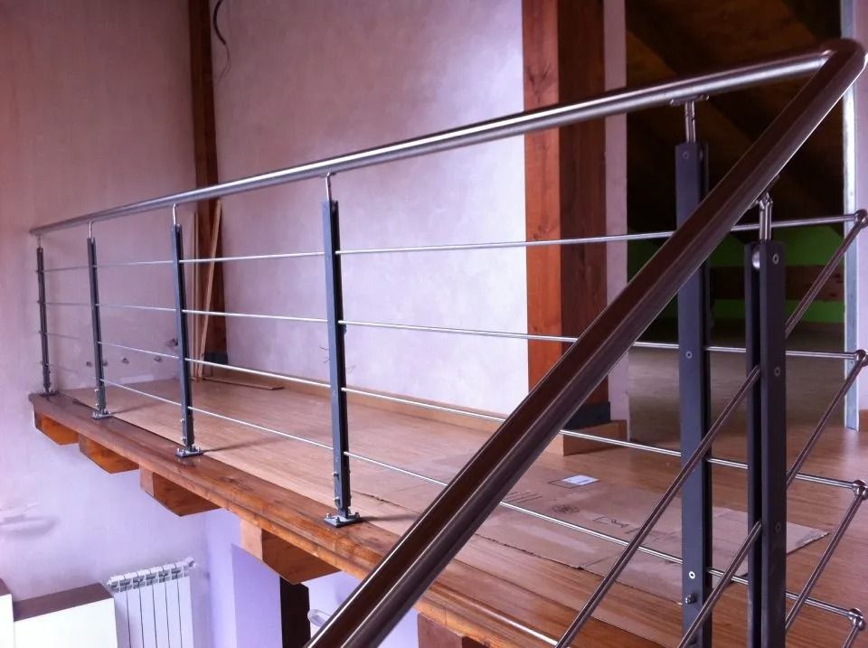 Ringhiera in acciaio inossidabile e metallo nero su un balcone in legno, ambientazione interna.