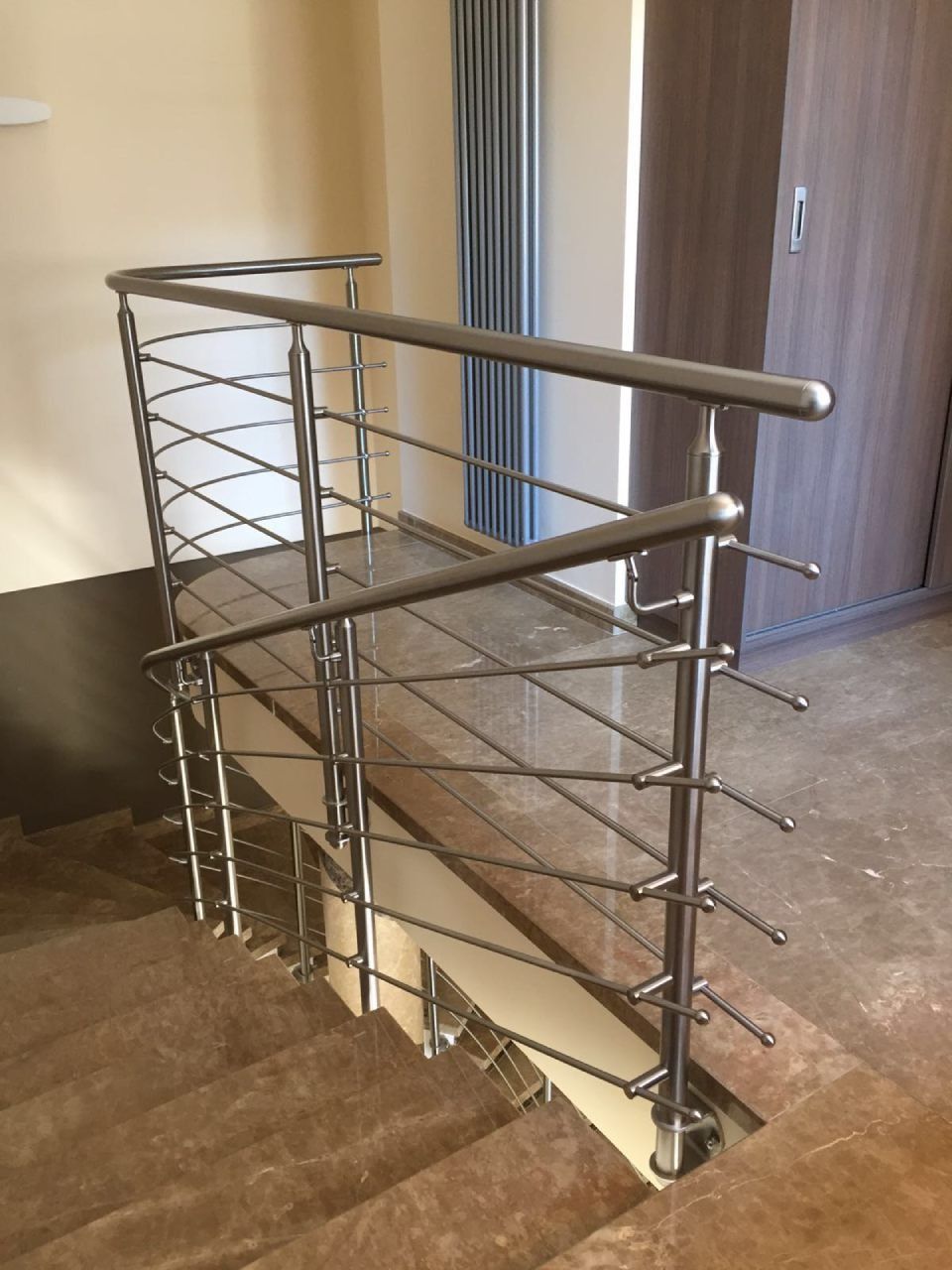Corrimano in acciaio inossidabile su una scala con fili a zig-zag; accanto a un muro e a un armadio.