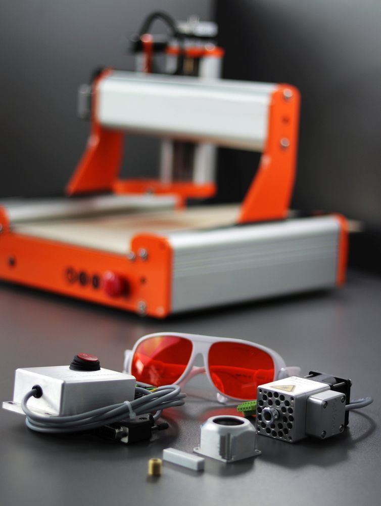 Incisore laser con montatura arancione e argento, occhiali di sicurezza e accessori.