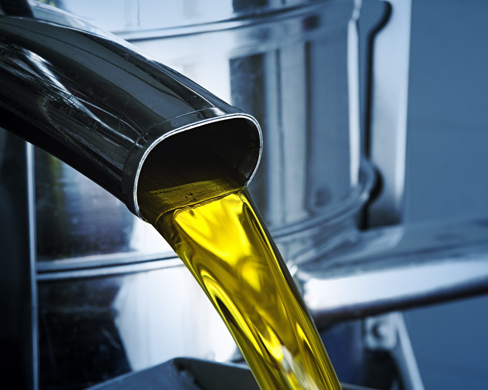 Fila di serbatoi di fermentazione in acciaio inossidabile in un magazzino, con un pallet di legno accatastato sullo sfondo.