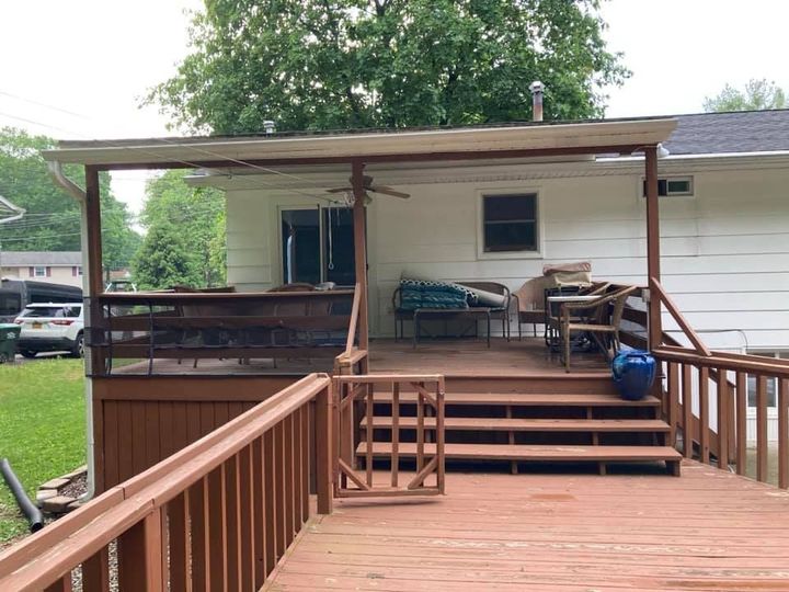 A white house with a wooden deck and stairs